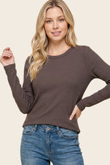 woman wearing a dark brown long sleeve ribbed top with a round neckline and light blue jeans