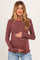 woman wearing a burgundy and white striped maternity long sleeve top and holding her baby bump