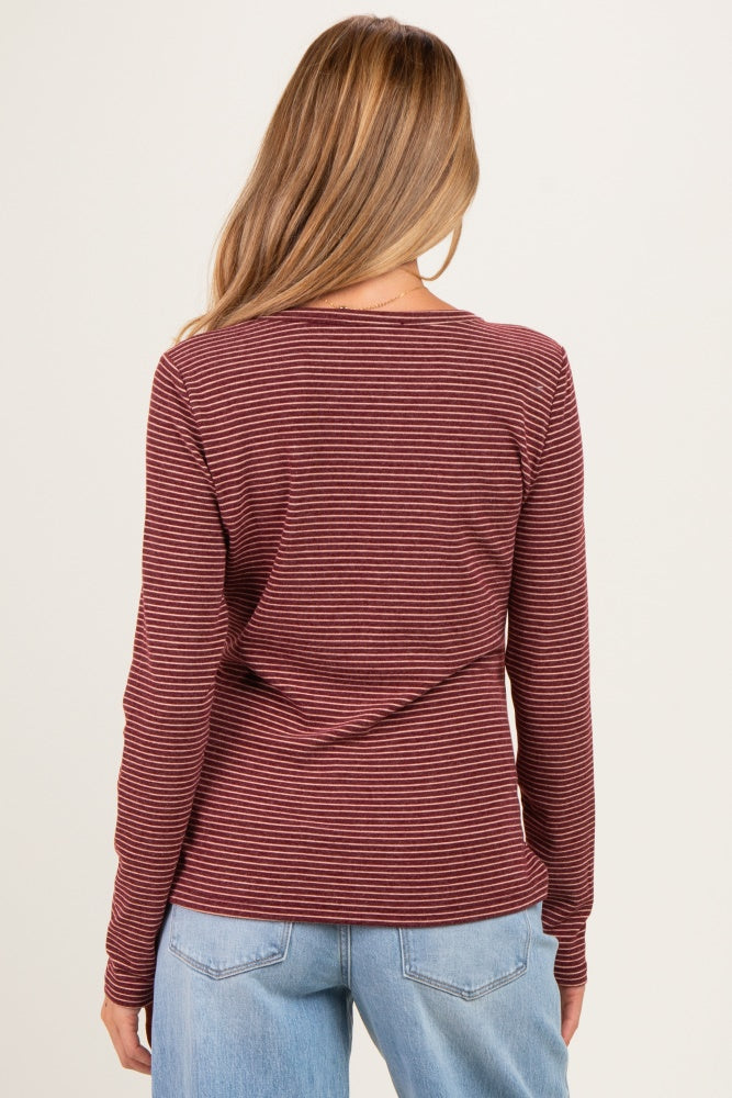 woman wearing a maroon and black striped maternity top with long sleeves, showing the back view