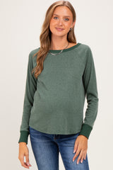 woman wearing a green maternity long sleeve top with a relaxed fit and a visible baby bump