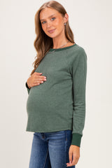 woman wearing a green maternity sweatshirt with a relaxed fit and long sleeves, holding her baby bump