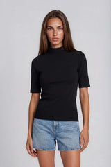 woman wearing a black short sleeve mock neck top and light blue denim shorts