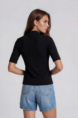 woman wearing a fitted black short sleeve top and light blue denim shorts, viewed from the back