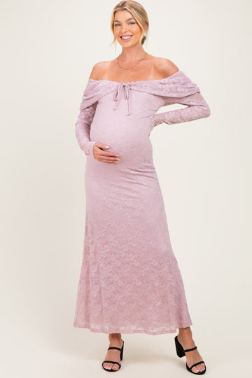 woman wearing a pink off-the-shoulder lace maternity dress and holding her baby bump