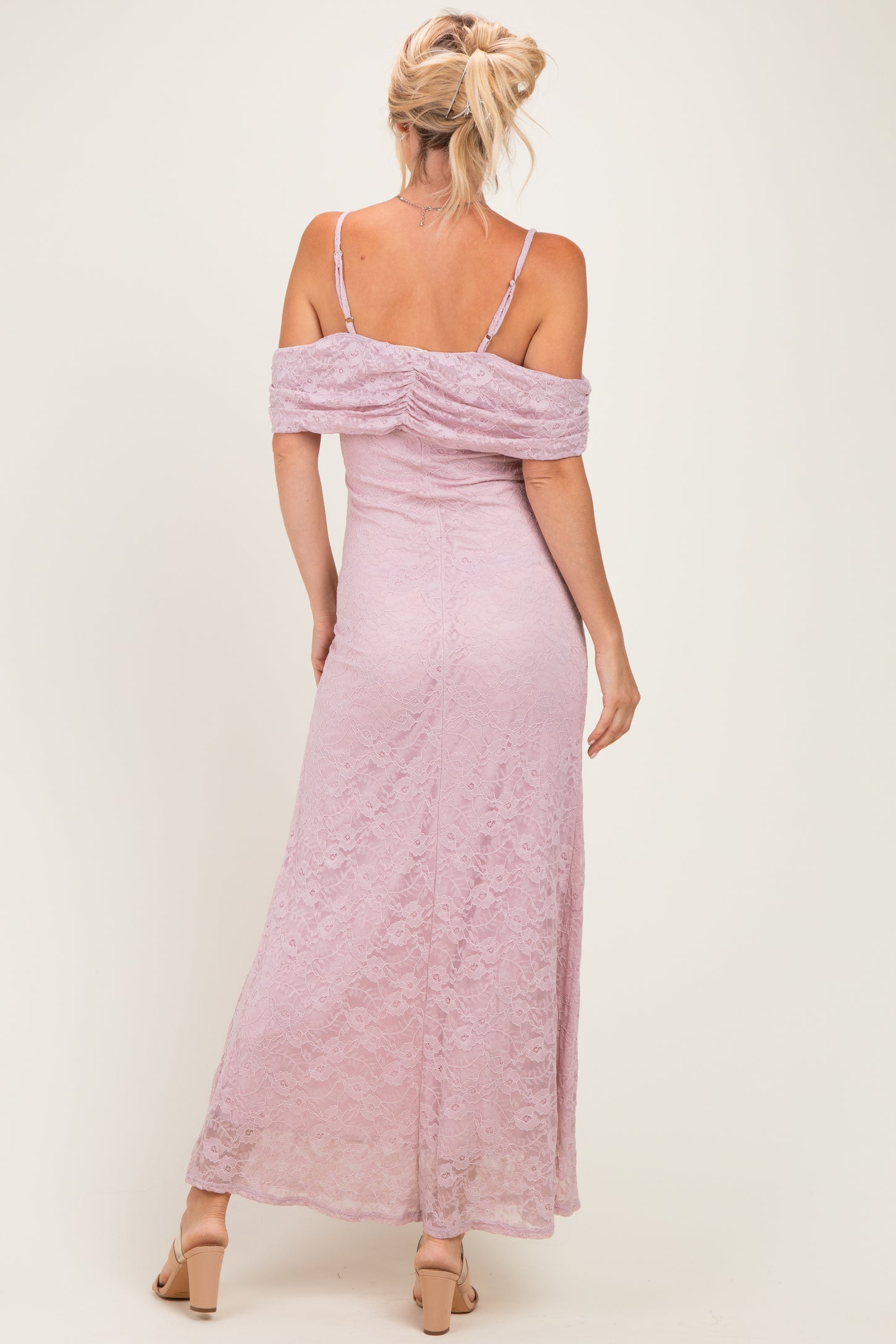 woman wearing a lavender lace off-the-shoulder maxi dress with a fitted silhouette and a ruched back design