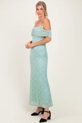 woman wearing a mint green lace off-the-shoulder maxi dress with a ruched bodice and spaghetti straps