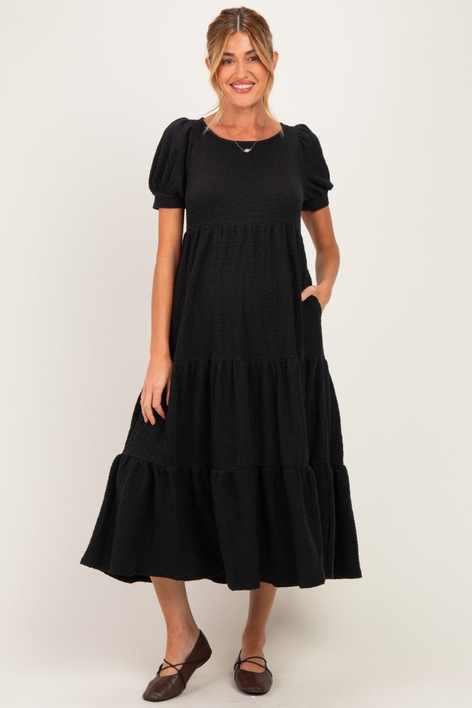 woman wearing a black tiered maternity dress with short puff sleeves and pockets