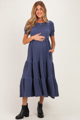 woman wearing a navy blue tiered maternity dress with short puff sleeves and a baby bump visible