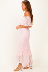 woman wearing a pink off-shoulder maxi dress with floral detailing and a flowy skirt, standing in profile