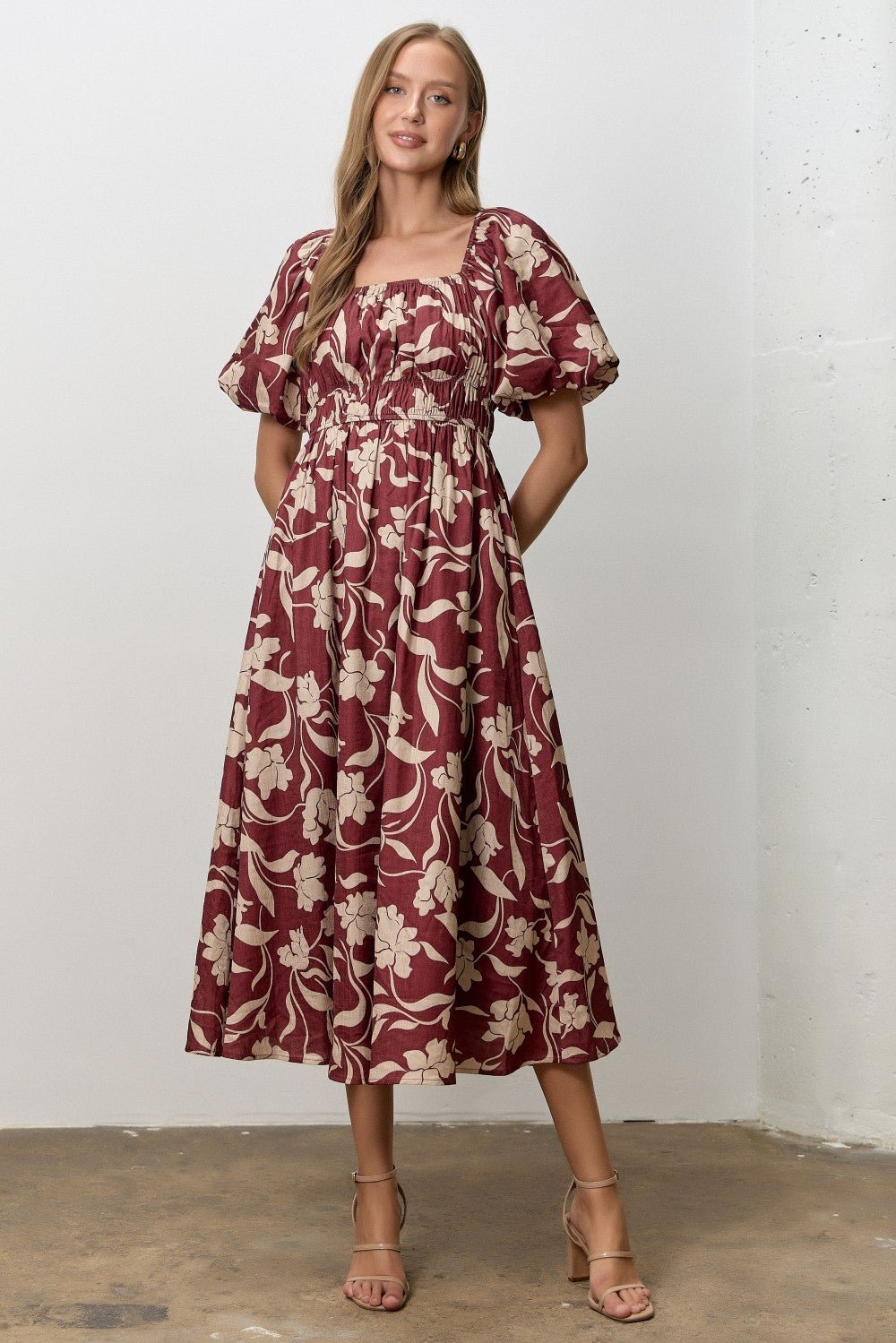 woman wearing a burgundy floral midi dress with puff sleeves and a fitted smocked bodice