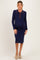 woman wearing a navy ribbed maternity dress with a button-up collar and long sleeves, showcasing her baby bump