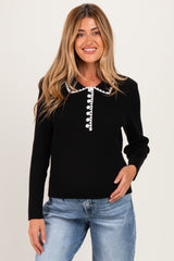 woman wearing a black ribbed maternity top with a white buttoned collar and long sleeves
