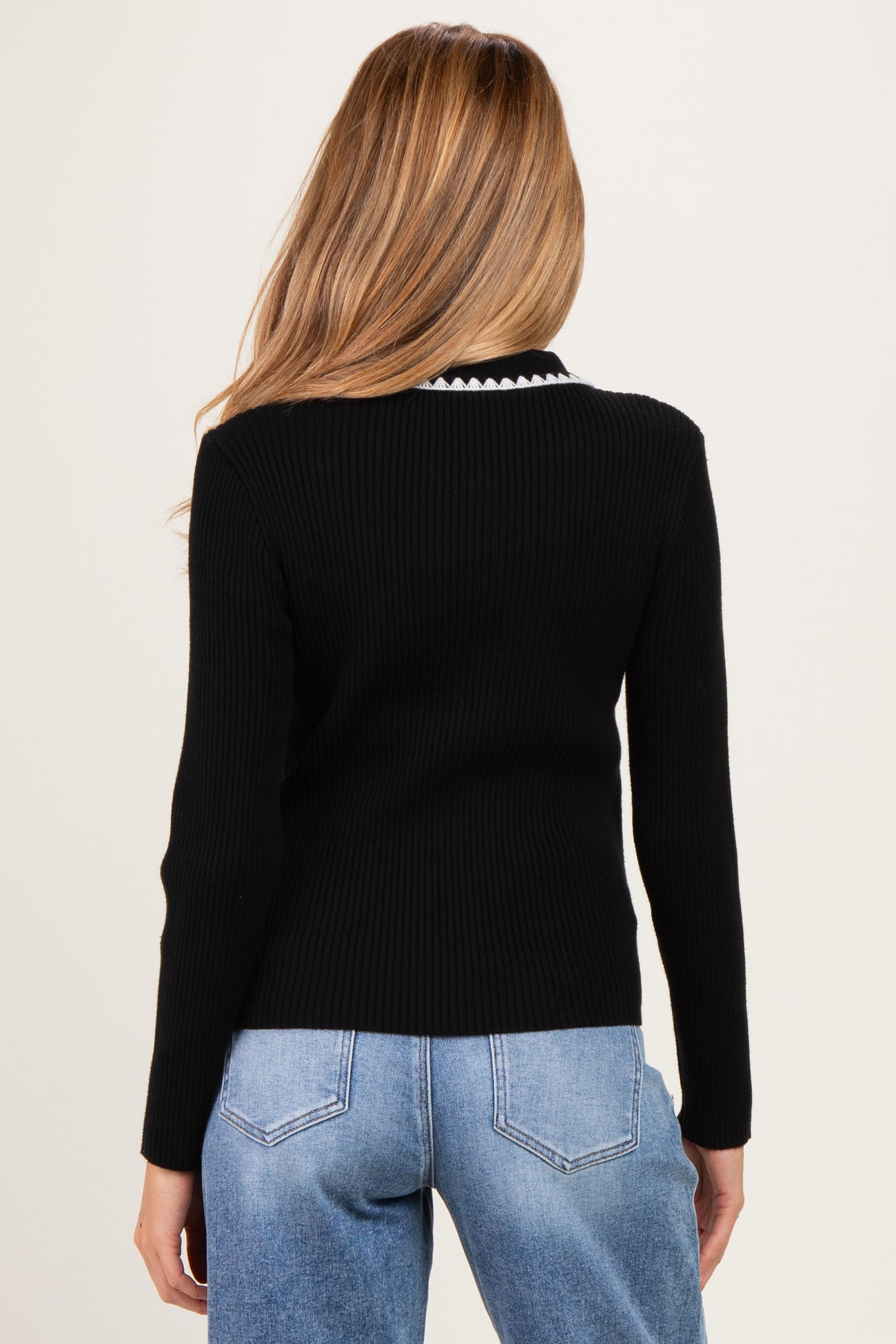 woman wearing a black ribbed maternity sweater with a contrast collar, viewed from the back
