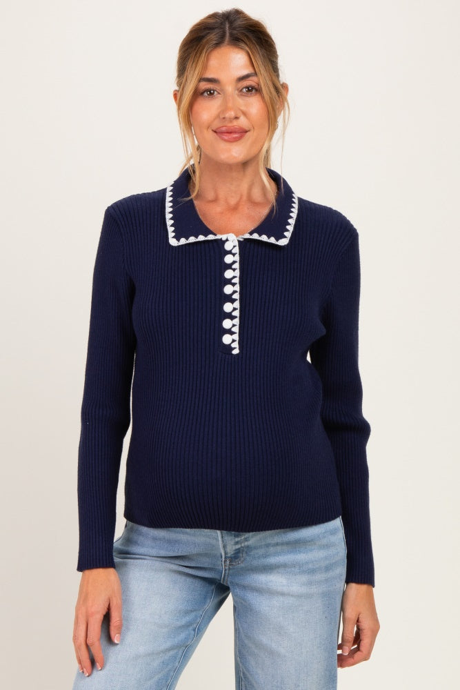 woman wearing a navy blue maternity sweater with a collared neckline and button details, showcasing her baby bump