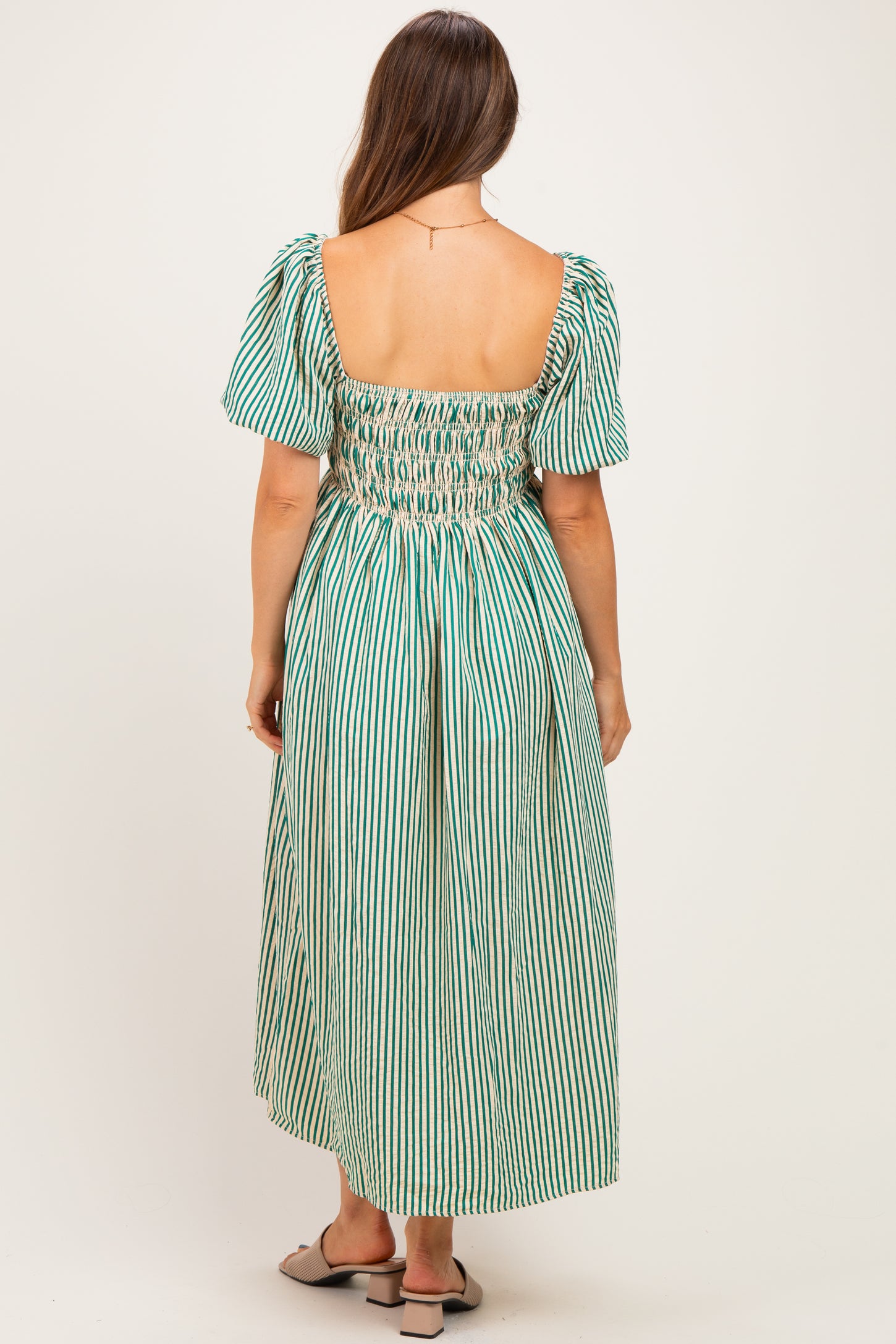 woman wearing a green and white striped maternity dress with a smocked back and puff sleeves