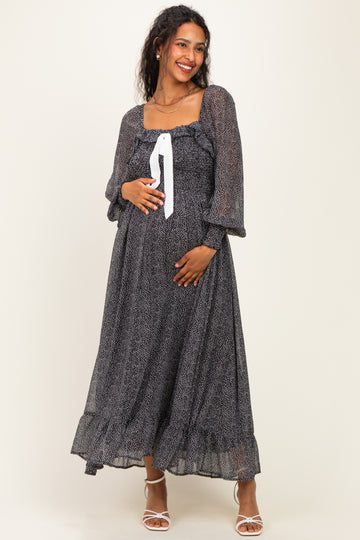 woman wearing a black and white patterned maternity dress with long sleeves and a tie at the neckline, showing her baby bump