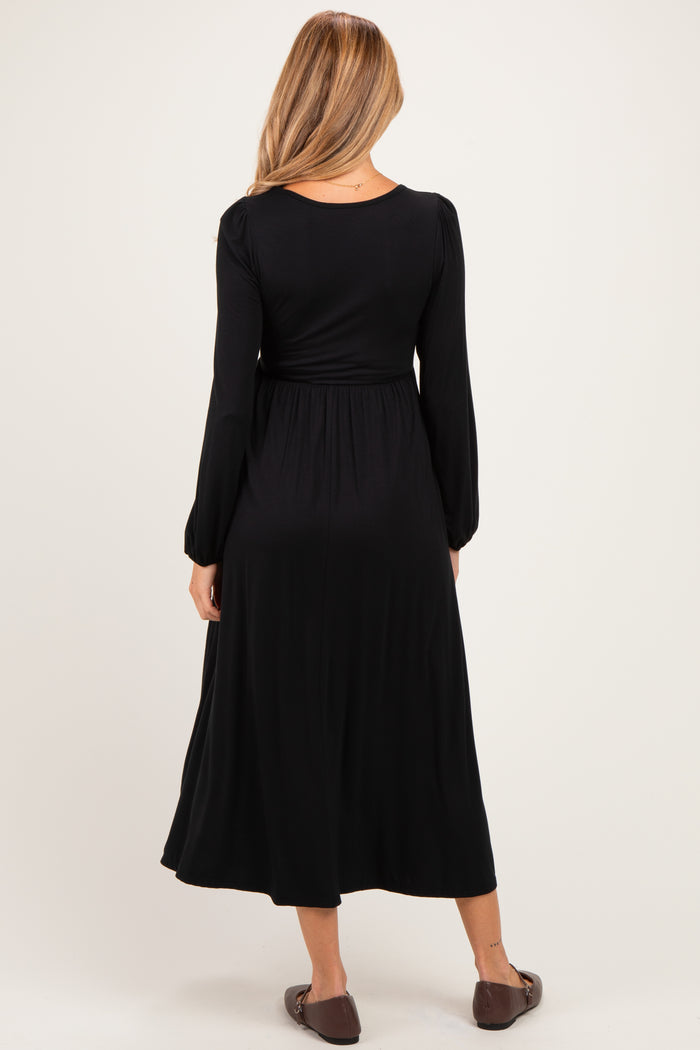 woman wearing a black long sleeve maternity dress with a flowing skirt, viewed from the back