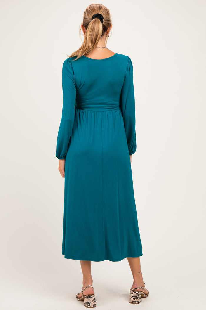 woman wearing a teal long sleeve maternity dress, shown from the back, with a relaxed fit and cinched waist