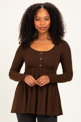 woman wearing a brown long sleeve henley tunic with a flared peplum and button details