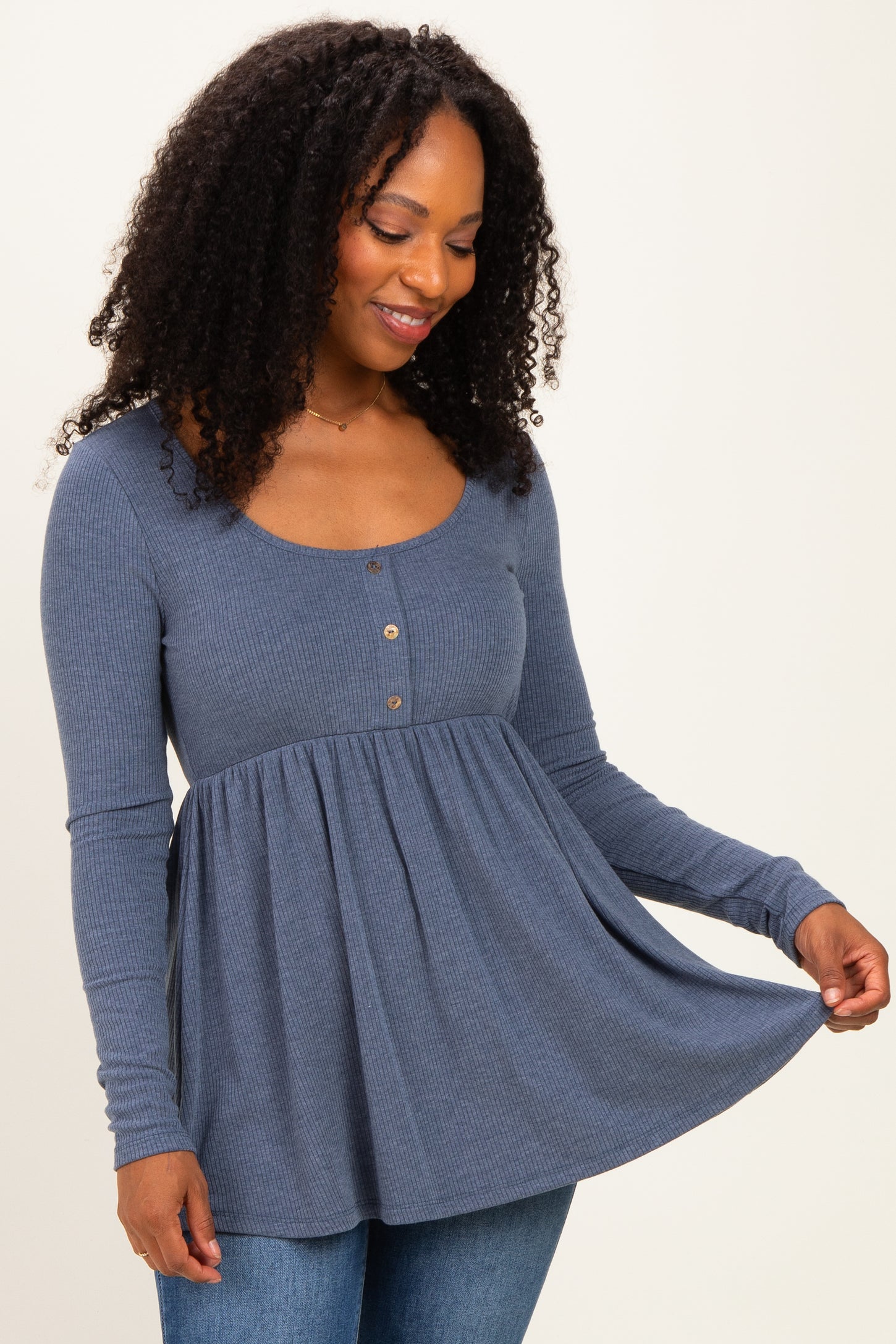 woman wearing a blue long sleeve button-up peplum top with a scoop neckline and ribbed texture