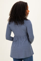 woman wearing a navy ribbed long sleeve top with a peplum hem and curly hair, shown from the back