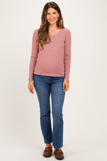 woman wearing a pink and white striped long sleeve maternity top with buttons and denim jeans, showing a baby bump