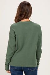 woman wearing a green long sleeve maternity sweater from the back with jeans