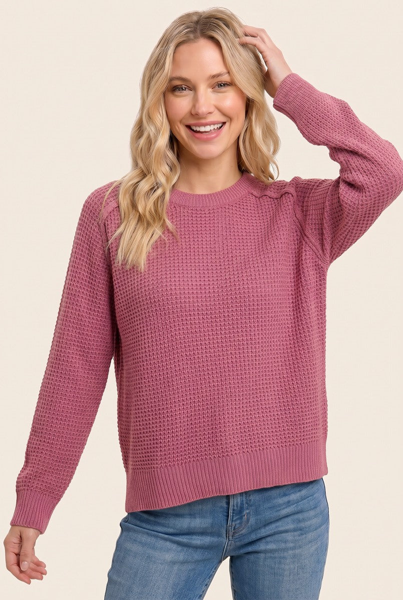 woman wearing a pink textured knit sweater with long sleeves and a relaxed fit
