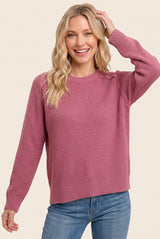 woman wearing a pink textured knit sweater with long sleeves and a relaxed fit