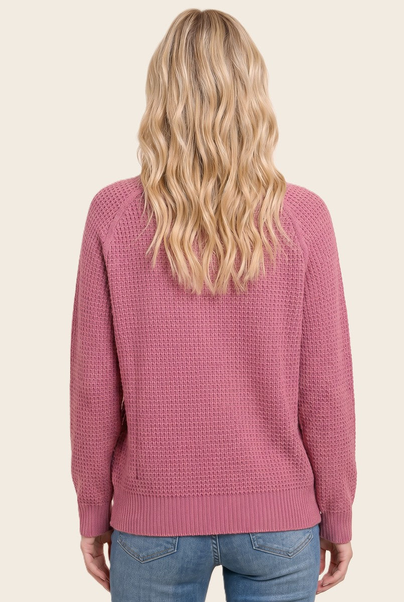 woman wearing a pink knitted sweater with a relaxed fit, viewed from the back, paired with light blue jeans