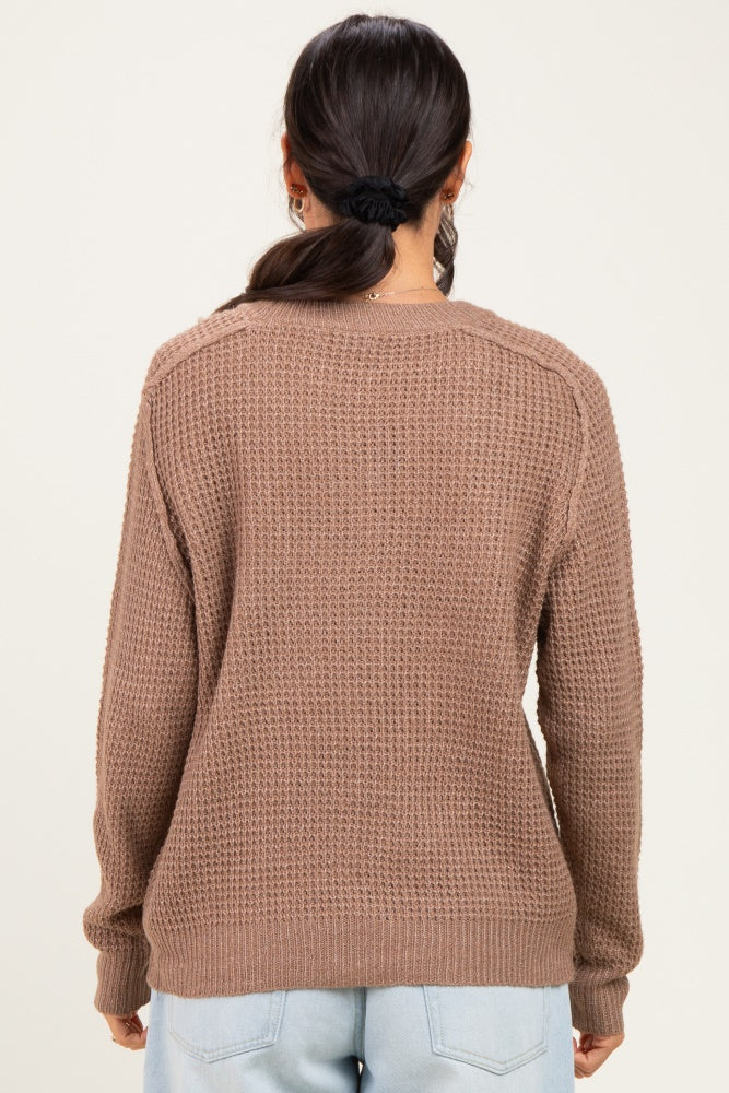 woman wearing a brown textured long sleeve sweater, seen from the back, paired with light blue jeans