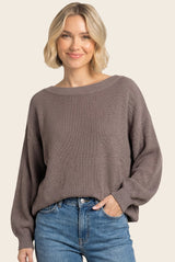 woman wearing a brown oversized knit sweater with balloon sleeves and light blue high-waisted jeans