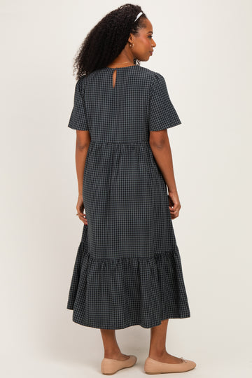 woman wearing a black and white checkered midi dress with short sleeves and a ruffled hem, viewed from the back