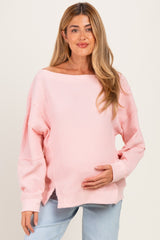 woman wearing a light pink ribbed maternity sweater and holding her baby bump