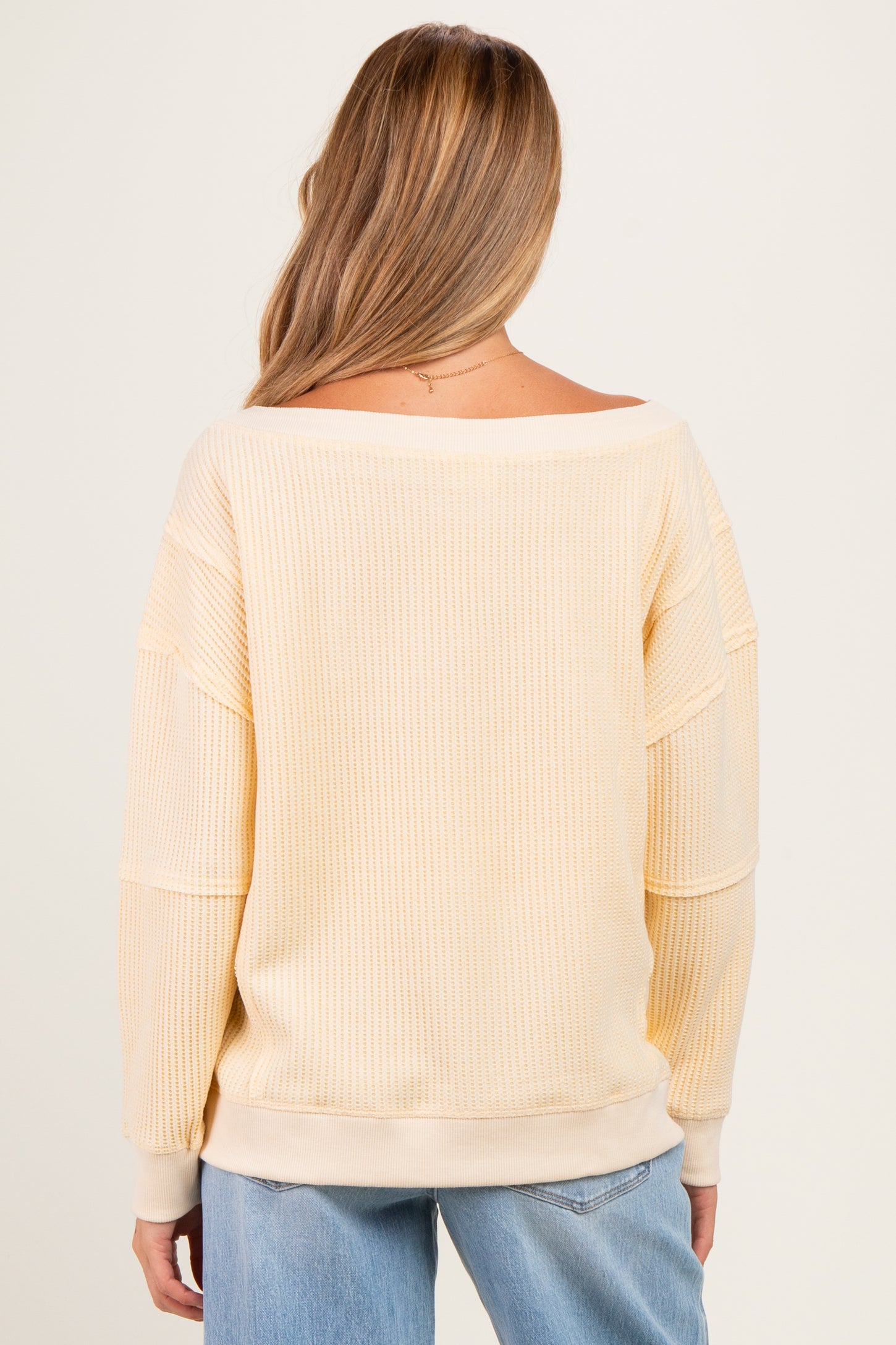 woman wearing a light yellow off-shoulder maternity sweater with a relaxed fit and long sleeves
