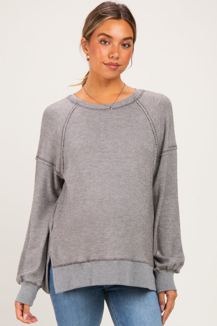 woman wearing a gray striped maternity sweater with long sleeves and side slits, styled with blue jeans