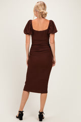 woman wearing a fitted brown midi dress with puff sleeves and ruching detail, shown from the back