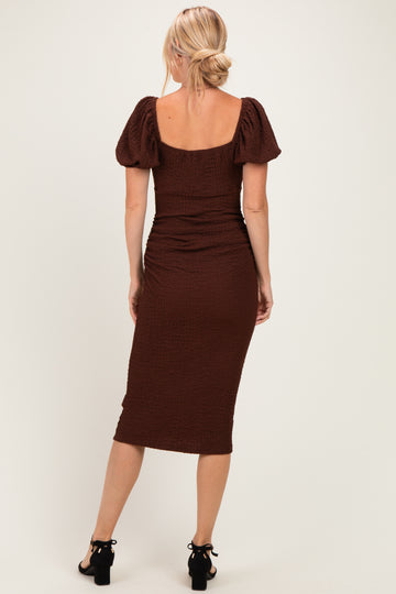 woman wearing a fitted brown midi dress with puff sleeves and ruching detail, shown from the back