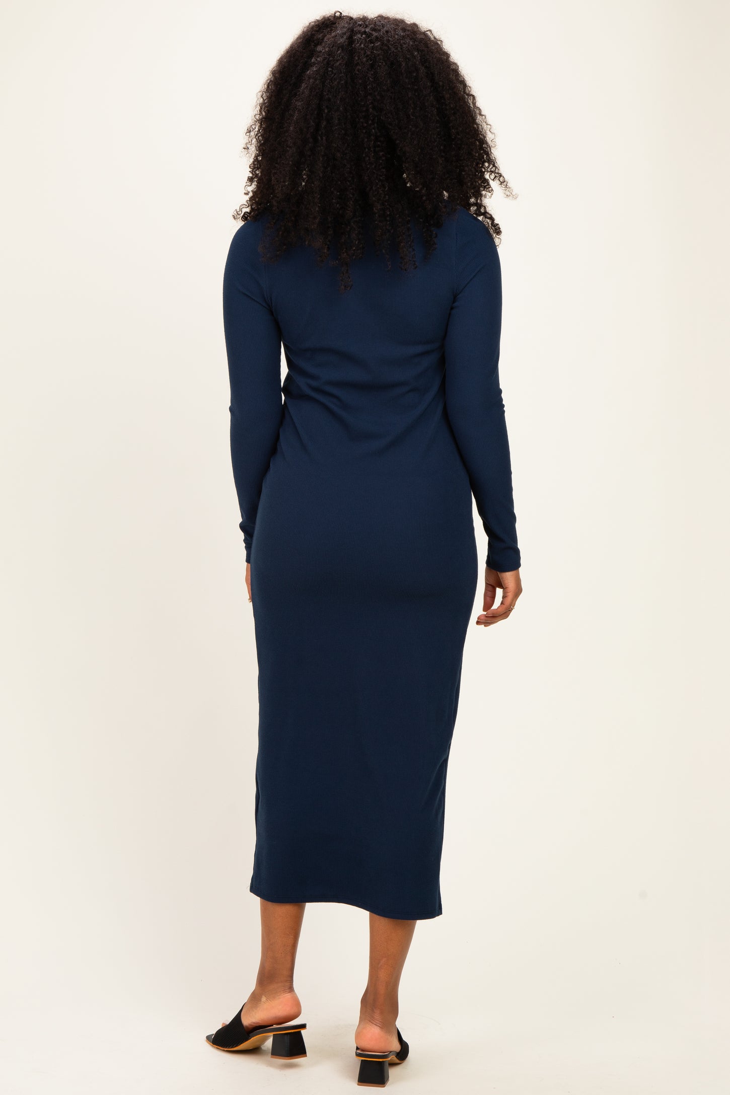 woman wearing a long sleeve navy blue ribbed midi dress, viewed from the back