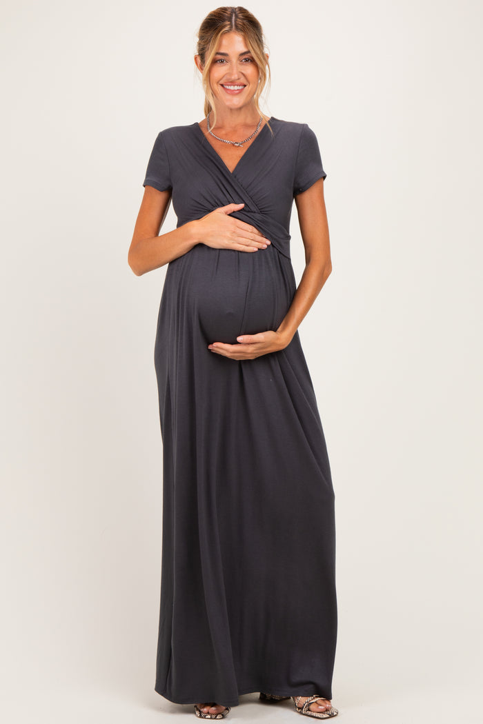 woman wearing a charcoal grey short sleeve maternity maxi dress and holding her baby bump