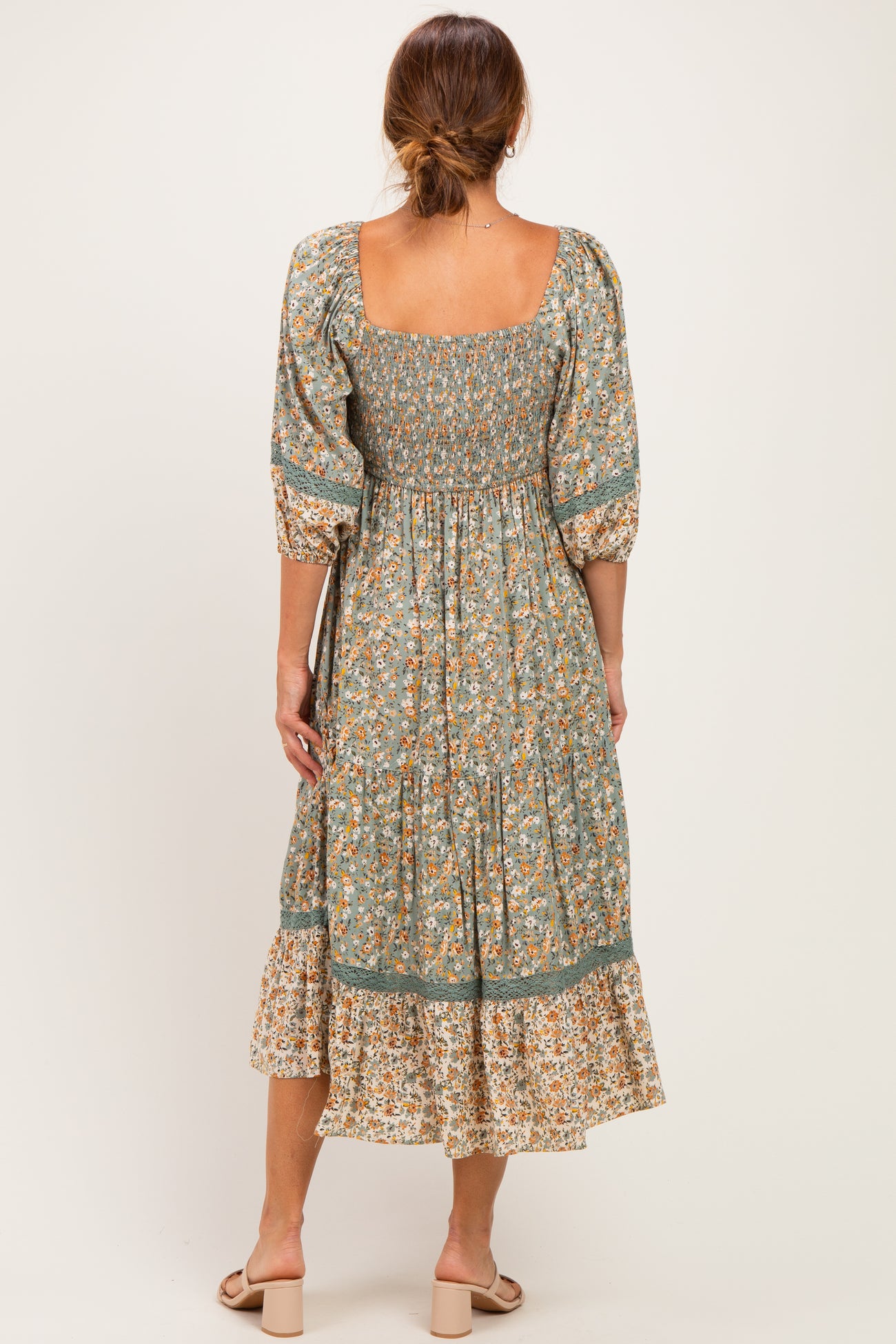 woman wearing a floral midi dress with a square neckline and puff sleeves, showing a gathered bodice and tiered skirt