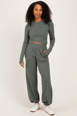 woman wearing a long sleeve olive green cropped top and matching wide-leg pants, paired with white sneakers