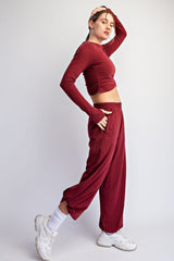 woman wearing a burgundy long sleeve crop top and matching loose-fit pants paired with white sneakers