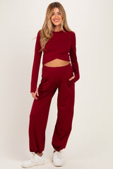 woman wearing a burgundy maternity crop top with long sleeves and matching wide-leg maternity pants