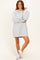 woman wearing a gray oversized sweatshirt dress with balloon sleeves and white sneakers