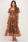 woman wearing a floral smocked maternity maxi dress with puff sleeves and tiered skirt