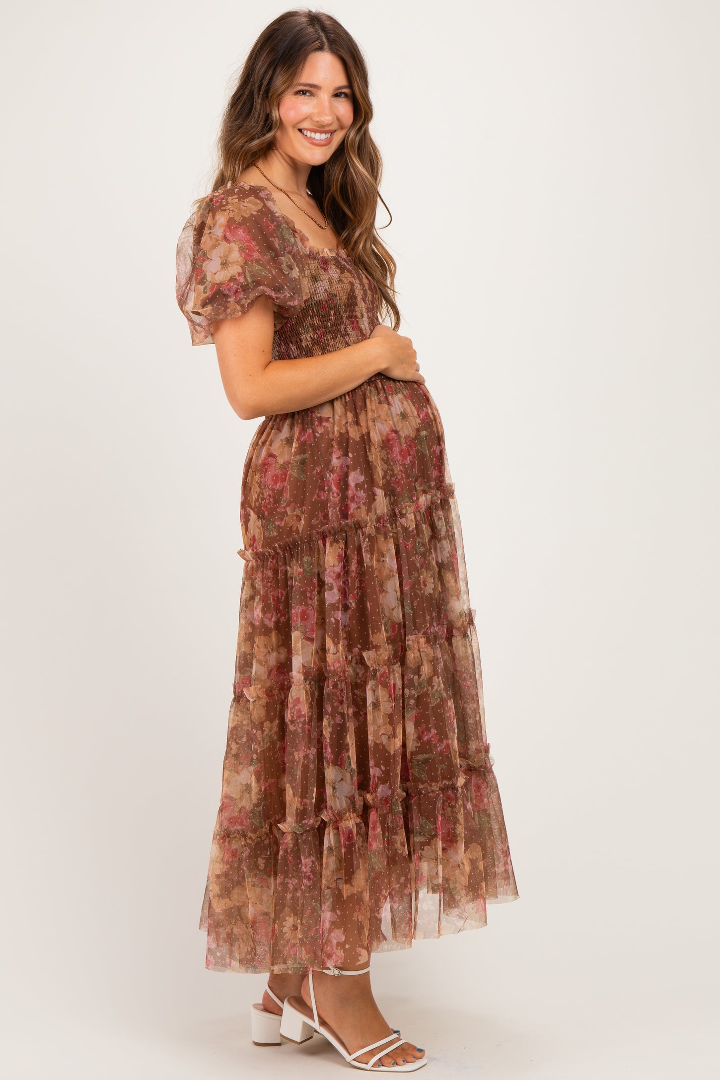 woman wearing a floral print maternity maxi dress with puff sleeves and a smocked bodice, showing her baby bump