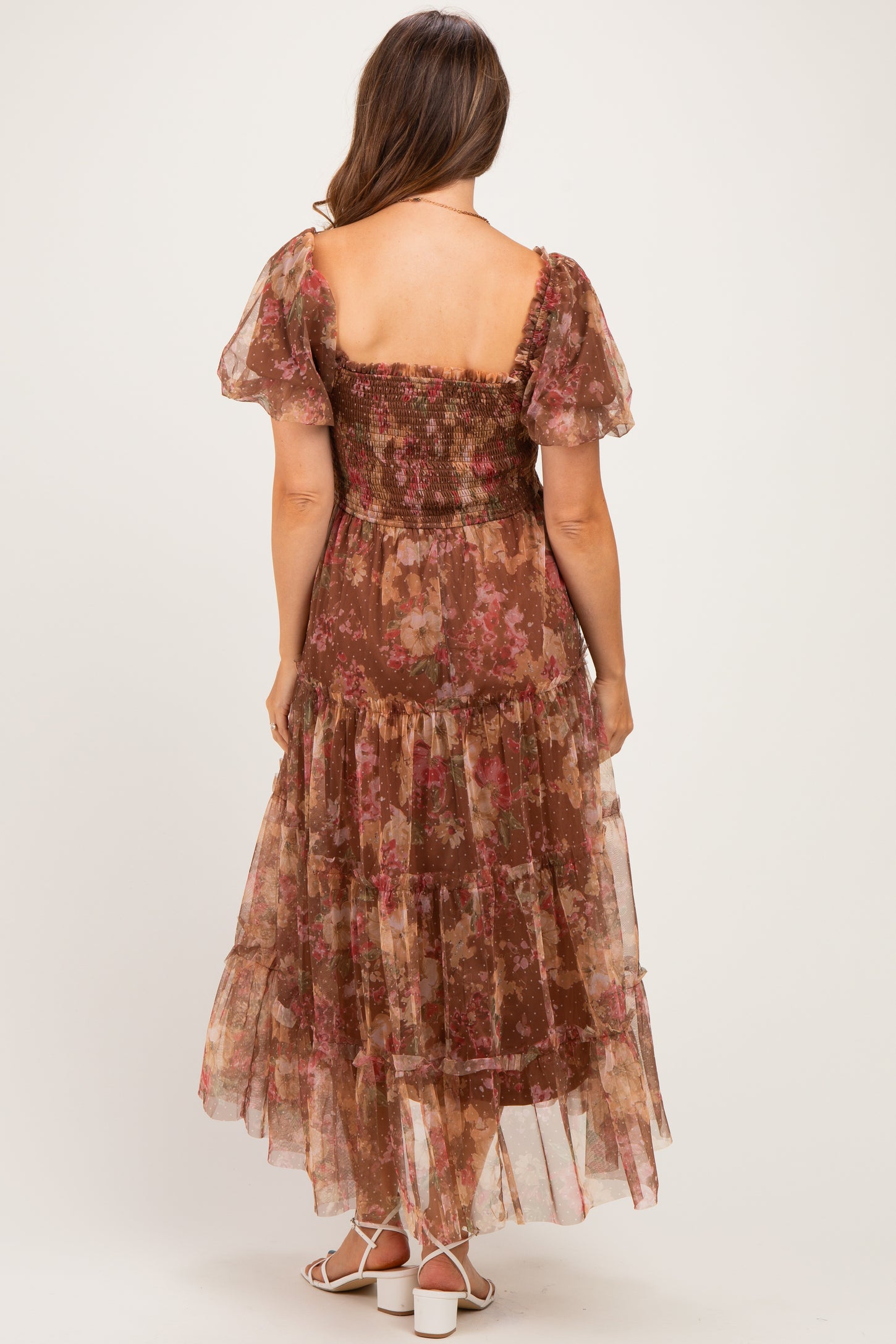 woman wearing a brown floral maternity maxi dress with a smocked bodice and tiered skirt, viewed from the back