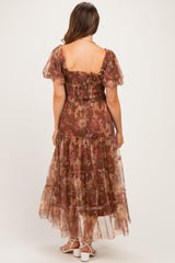 woman wearing a brown floral maternity maxi dress with a smocked bodice and tiered skirt, viewed from the back