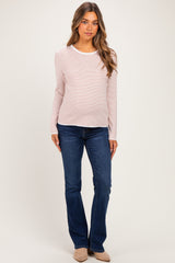 woman wearing a light pink and white striped long sleeve maternity top with a visible baby bump and blue jeans